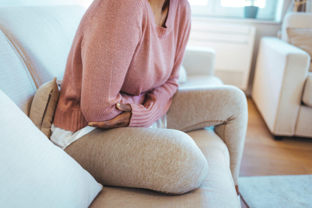 oung woman lying down on her bed and suffering from period pains at home